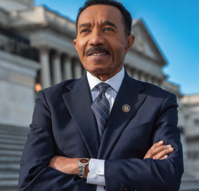 Congressman Kweisi Mfume stands on steps of US Capitol with arms folded. Image by P.A. Greene.